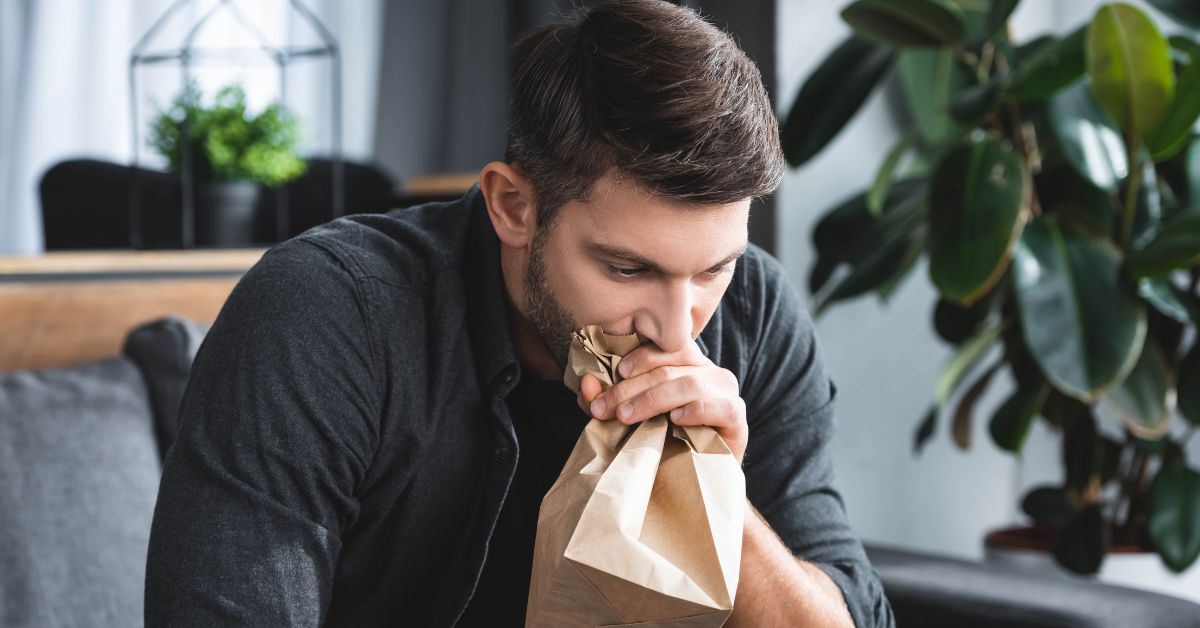 a man breathing through a paper bag