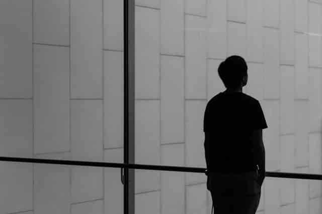 ALT TEXT: Back of a person looking through the glass. Via Unsplash.com